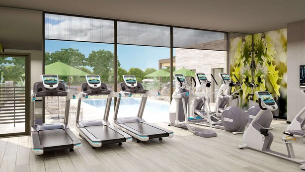 A modern gym with treadmills, stationary bikes, and elliptical machines.
