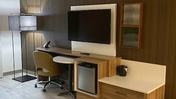 Un espacio de oficina moderno con un escritorio, silla, computadora y una televisión de pantalla plana montada en la pared.