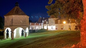 A historic building with a stone tower and arched entrance, surrounded by well-maintained lawns and trees.