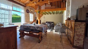 A rustic room with a bed, a dining table, a sofa, and a kitchen area.