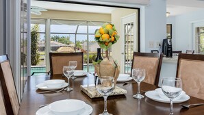 A dining table set for six with white plates, glasses, and a centerpiece of oranges and leaves. - Family-friendly villa w/bikes & pool table; Gulf access! Villa Lilly - SWFL Rentals (Cape Coral)
