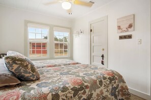 A bedroom with two beds, a window, a door, and wall decorations.