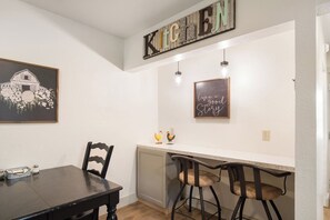 A kitchen with a chalkboard sign, a framed picture, and bar stools. - Cherry Street | Near Main | Gas BBQ | Couples (Bandera)