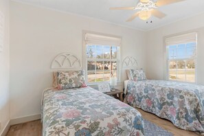 A bedroom with two beds, a ceiling fan, and windows with white frames. - Cherry Street | Near Main | Gas BBQ | Couples (Bandera)