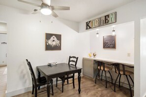 A dining area with a table and chairs, a ceiling fan, and wall-mounted artwork. - Cherry Street | Near Main | Gas BBQ | Couples (Bandera)