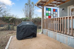 A covered Weber grill in a backyard with a wooden deck and a house in the background. - Cherry Street | Near Main | Gas BBQ | Couples (Bandera)