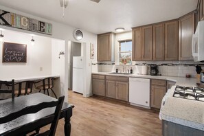 A compact kitchen with wooden cabinets, a white refrigerator, a sink, and a gas stove.