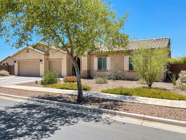 A residential house with a garage, a driveway, and a landscaped garden with various plants. - Desert Oasis with pool and spa in gated community (Laveen)