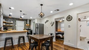 Una cocina moderna con una mesa de comedor de madera, sillas negras e iluminación colgante.