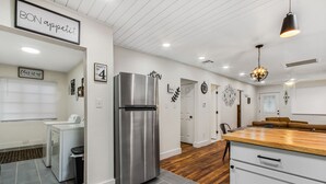 Una cocina moderna con un refrigerador de acero inoxidable, una encimera de madera y un armario blanco.