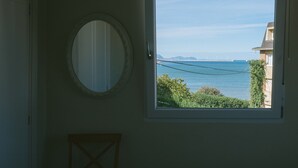 A room with a large window offering a view of the sea and a bridge. - "Amaluz Ocean Villa Bilbao Beach for families and groups of friends". (Getxo)