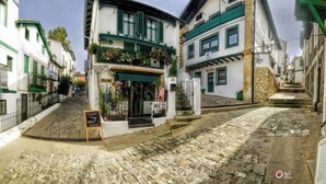 A cobblestone street with buildings featuring traditional architecture, including a shop with a green awning and flower boxes. - "Amaluz Ocean Villa Bilbao Beach for families and groups of friends". (Getxo)