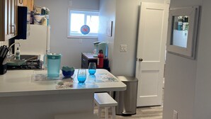 Cocina compacta con encimera blanca, un pequeño comedor y una ventana con vistas.
