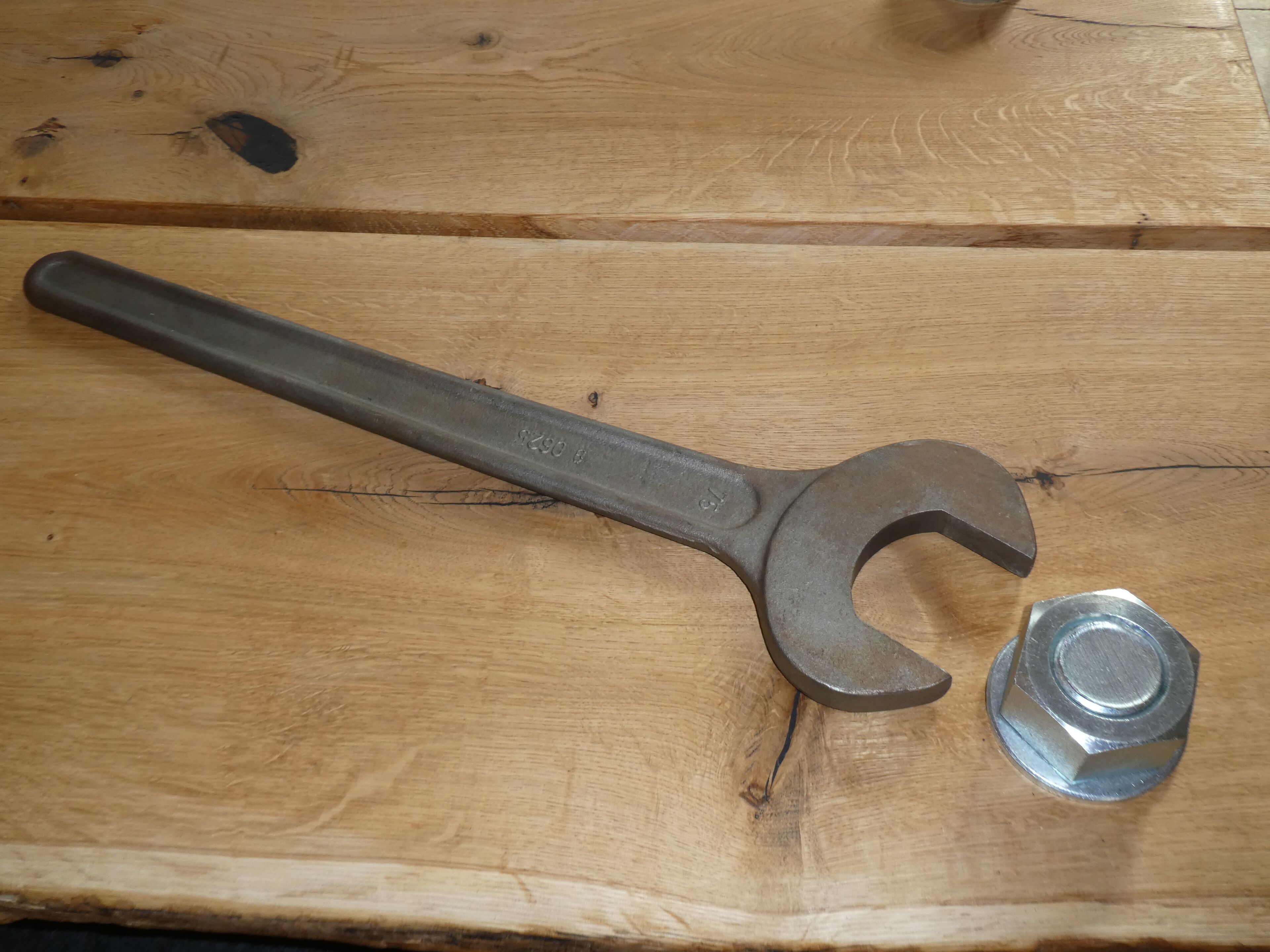 Une clé à molette et un écrou sur une surface en bois.