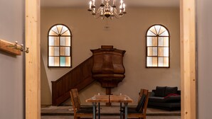 A room with a wooden staircase, a grand piano, a chandelier, and a sofa.