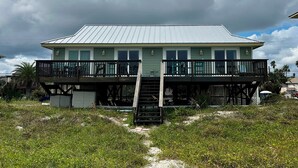 A two-story building with a metal roof, a balcony on the upper floor, and a staircase leading to the entrance. - 3 bed/2 bath private oceanfront home with direct beach access on Amelia Island! (fernandina beach)