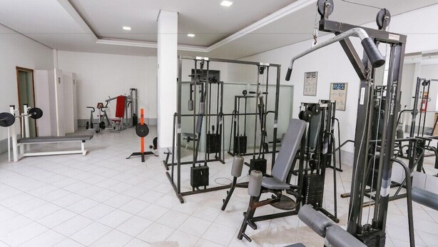 Et fitnessrum med diverse træningsmaskiner, en vægtbænk og en spejlvæg.