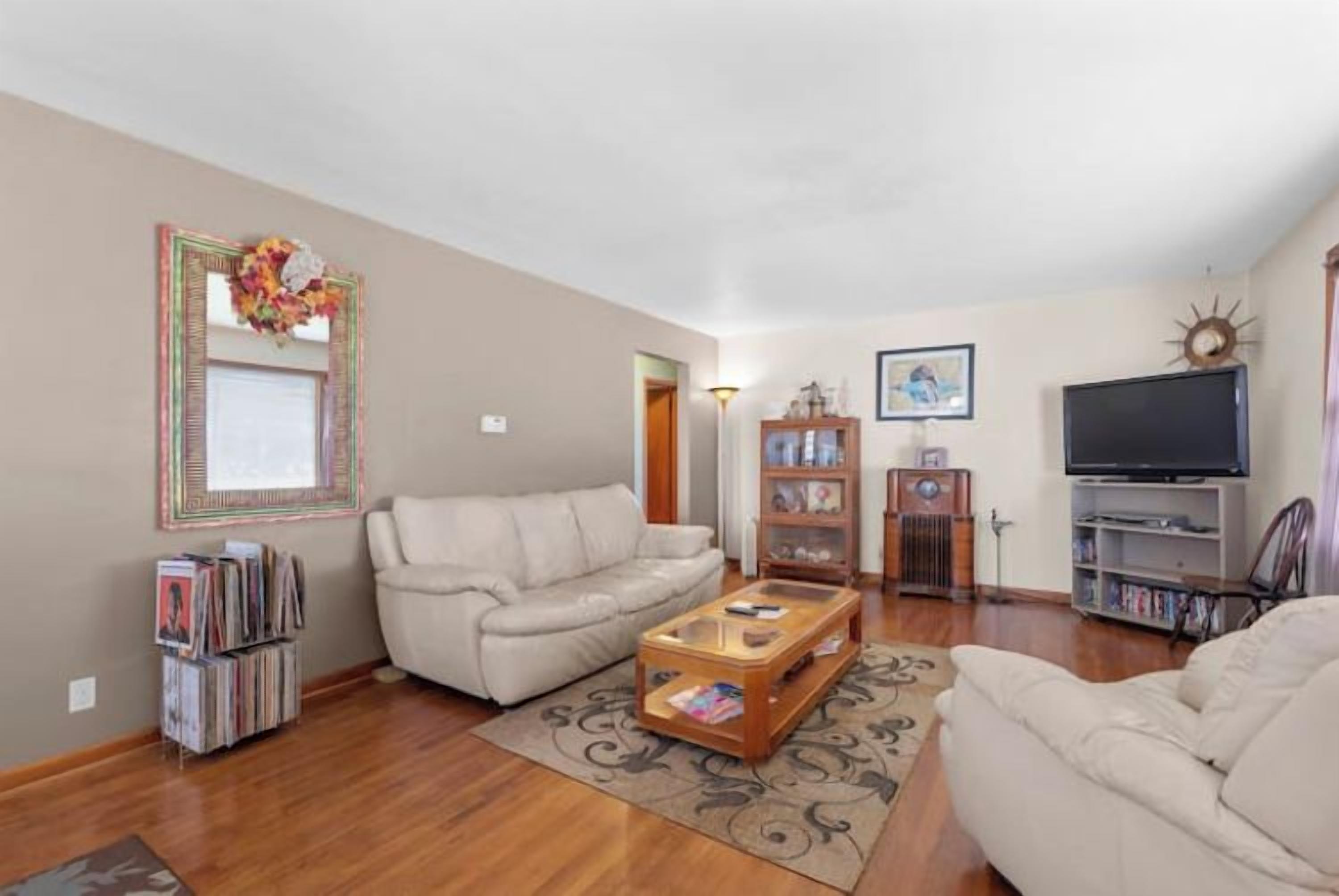A living room with a sofa, coffee table, bookshelf, and a television.