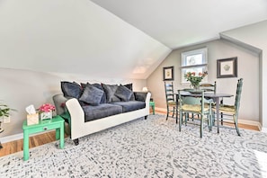 Un acogedor dormitorio tipo loft con un sofá gris, una mesa de comedor con sillas y una alfombra estampada.