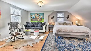 A bedroom with a bed, a rocking chair, a sofa, a rug, and a painting on the wall. - Trolley Apt Upper: Steps to Village Trail & Canal! (Pittsford)