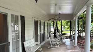 A covered porch with white columns, a ceiling fan, and a hanging lantern.