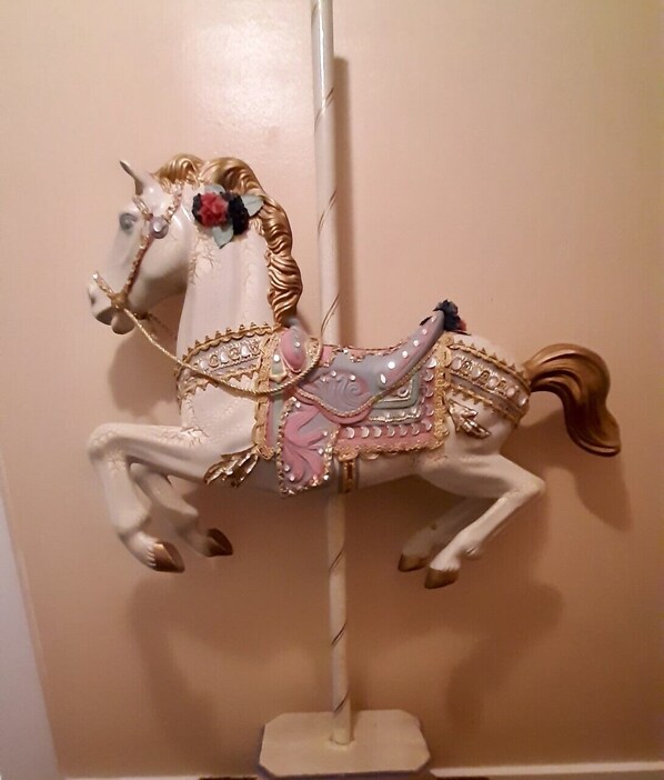 A carousel horse with decorative elements and a pole.