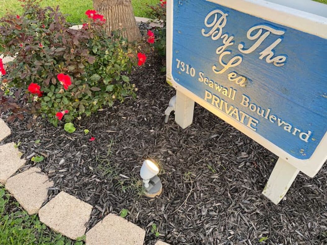 A sign for 'By The Sea' at 7310 Seawall Boulevard, indicating a private location.