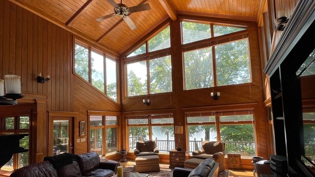 Un salón espacioso con techo alto, ventanas grandes y chimenea.