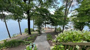 Una escalera de madera que lleva a una zona junto al lago, con vista al agua y árboles.