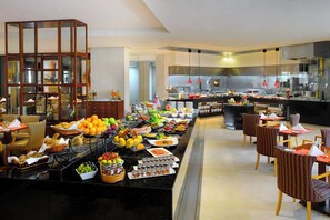 Zona de bufé con una variedad de alimentos y una cocina al fondo.