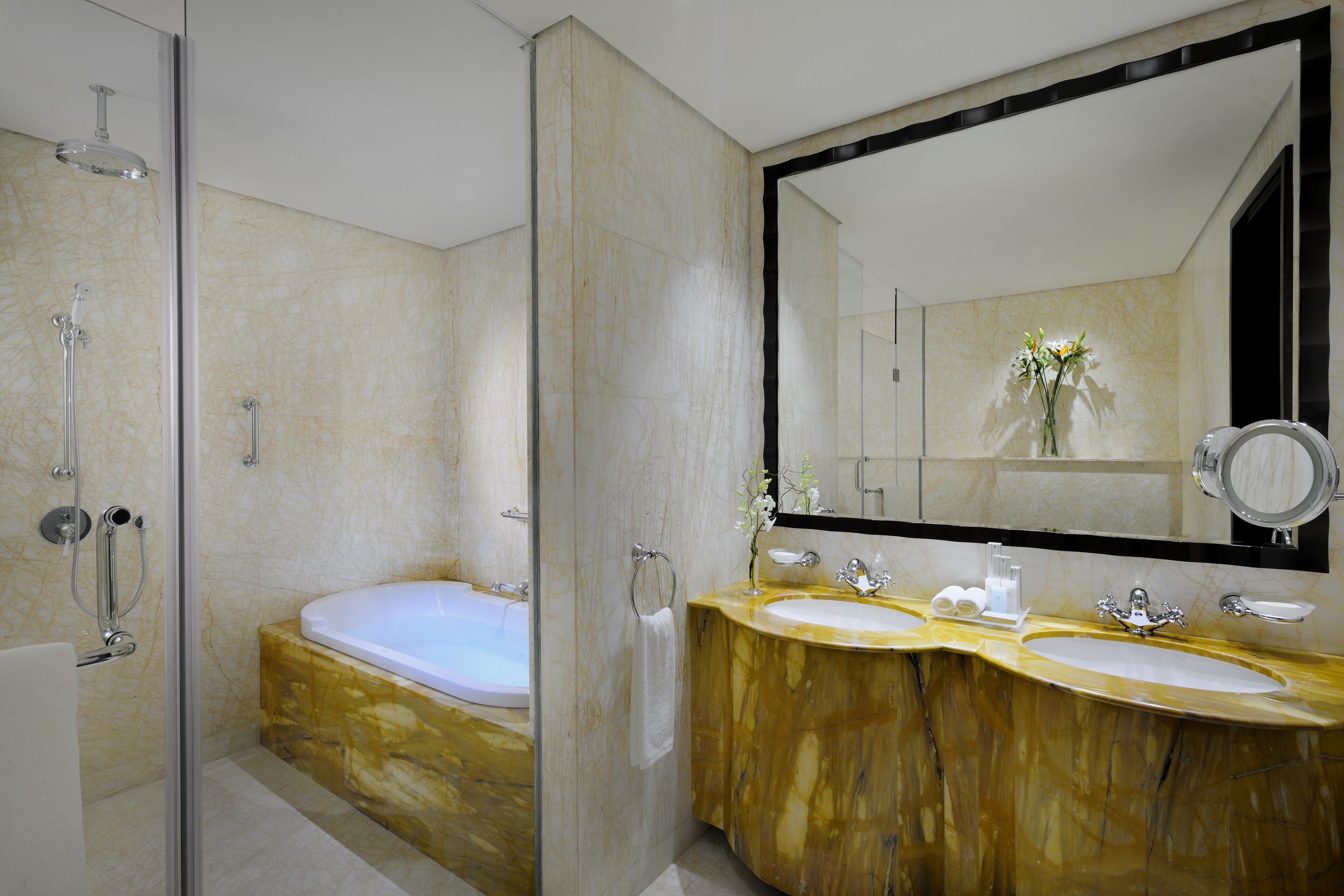 Une salle de bain moderne dotée d’une douche à parois de verre, d’un meuble-lavabo à deux vasques et d’un grand miroir.