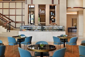 A lobby with a central counter displaying pastries and a sign reading "The Plaza Lobby & Cafe". - Crowne Plaza Dubai Jumeirah by IHG (Dubai)