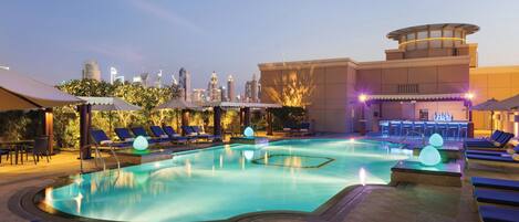 A rooftop pool with lounge chairs and a city skyline in the background.
