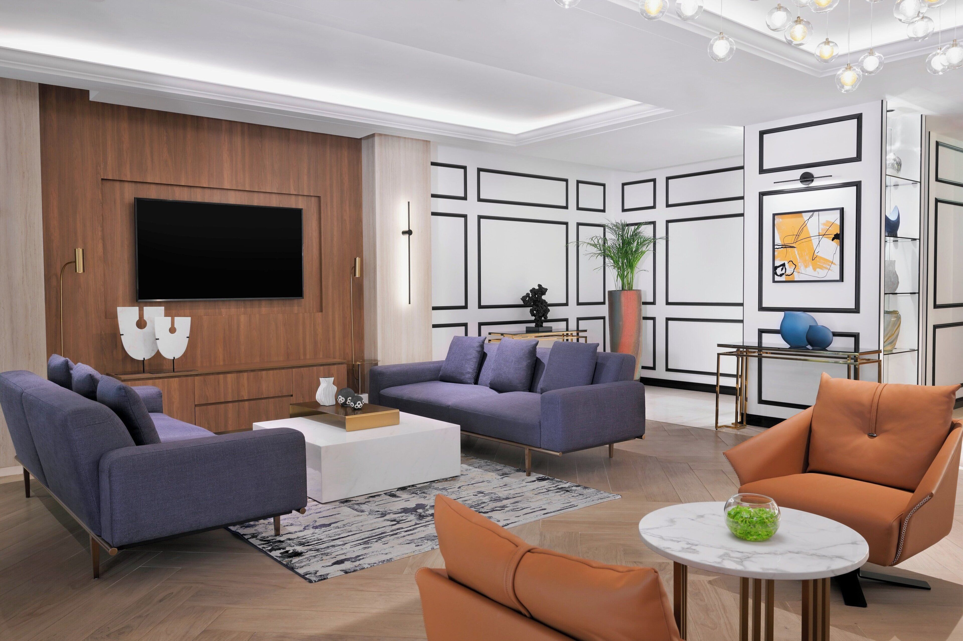 A modern living room with a flat-screen TV, two sofas, a coffee table, and a small round table with a green bowl.