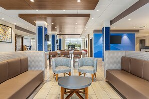 A modern hotel lobby with a central seating area, a dining table, and a large screen. - Holiday Inn Express and Suites Ukiah by IHG (Ukiah)