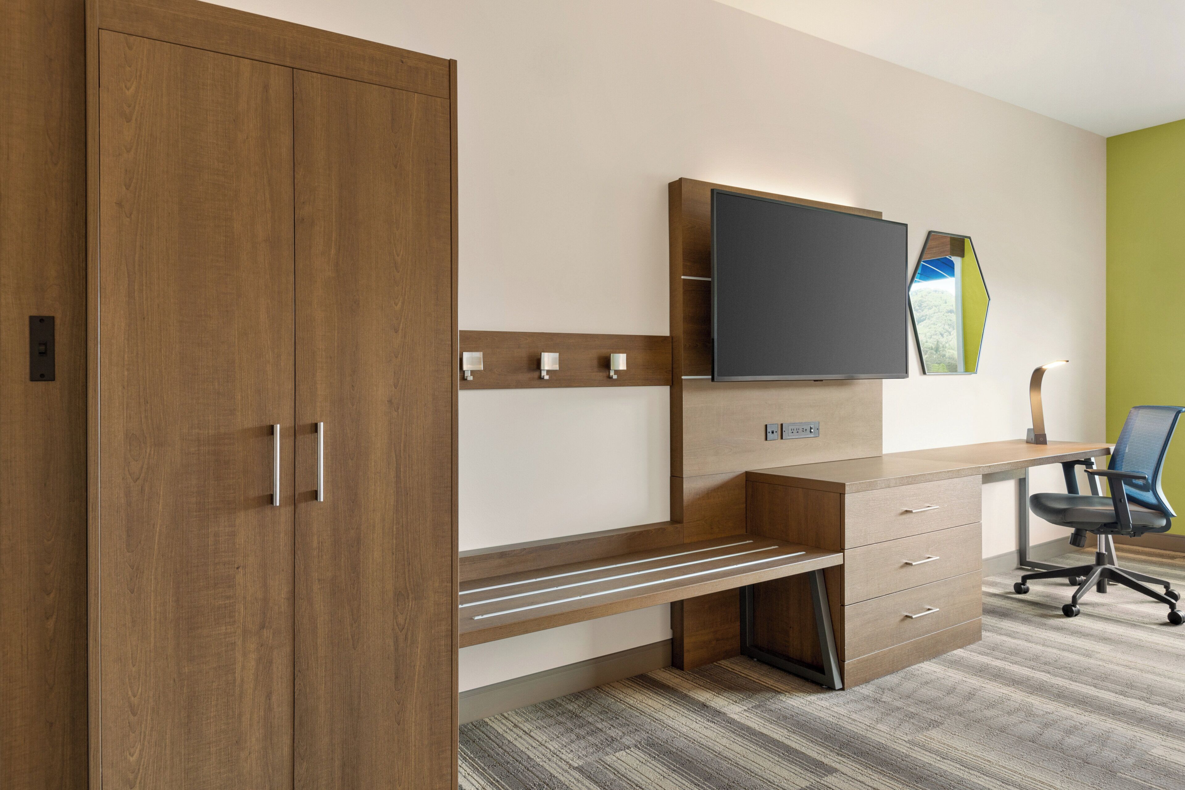 A modern office space with a wooden desk, a flat-screen TV, and a chair.