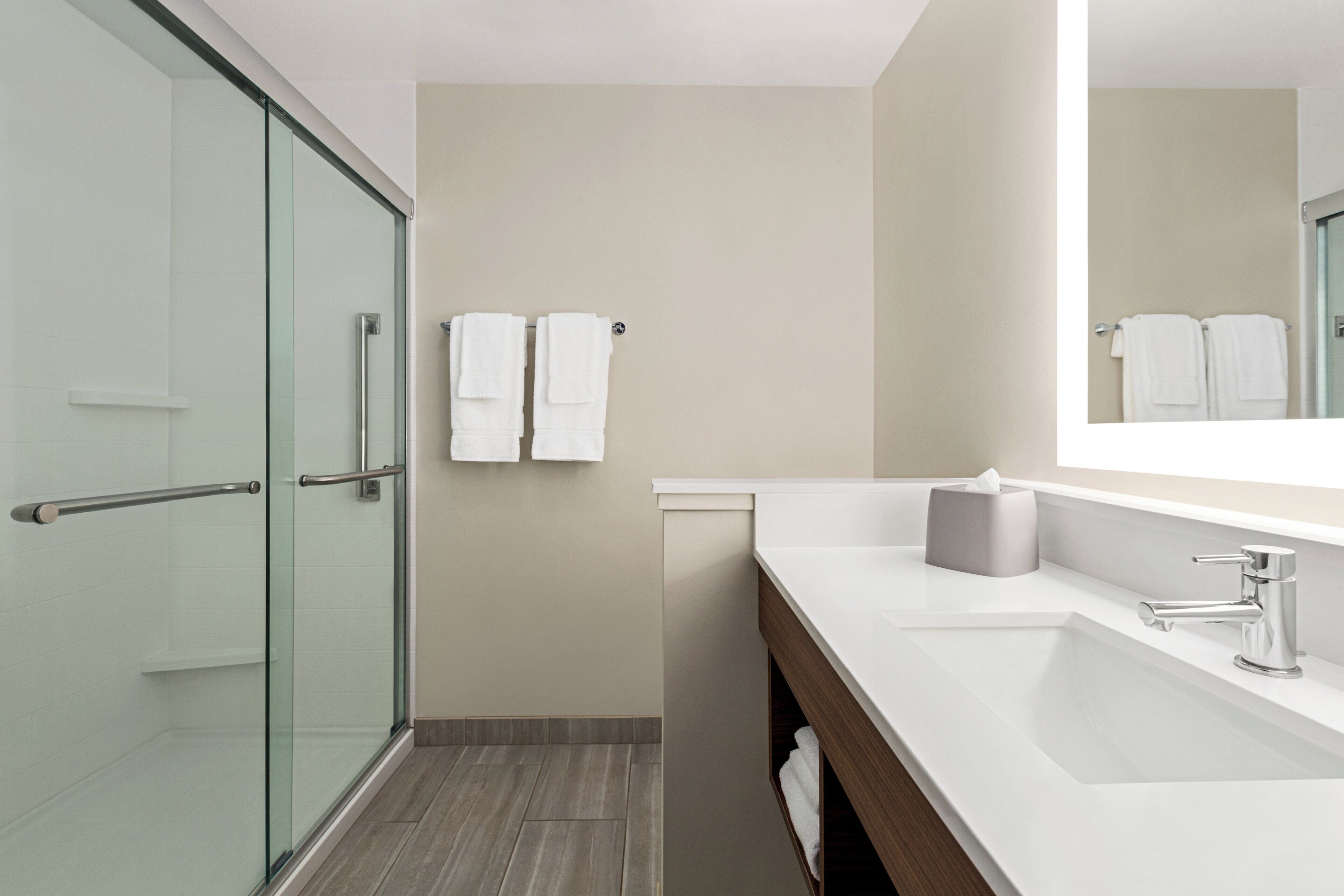 A modern bathroom with a glass shower enclosure, a white sink, and a mirror.