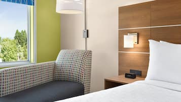 A hotel room with a bed, a nightstand, a lamp, and a chair.