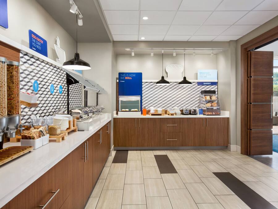 A modern breakfast area with a counter, food dispensers, and a bakery section.