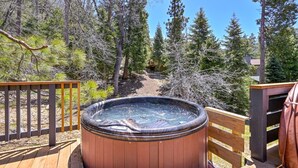 Ein Whirlpool auf einer Holzterrasse, umgeben von Bäumen.