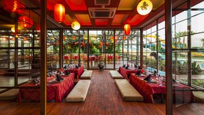 A restaurant with a wooden floor, red tablecloths, and a view of a water park. - Club Hotel Turan Prince World Select Villa (Manavgat)