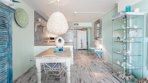 Un comedor con mesa y sillas de madera, una lámpara colgante y un expositor de vidrio con objetos decorativos.