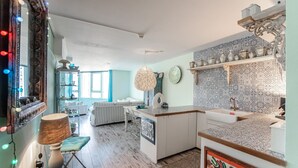 Una cocina moderna con una isla central, un área de comedor con un sofá y un ventanal amplio.