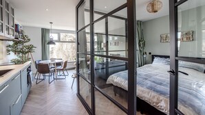 Un dormitorio moderno con una cama grande, un separador de vidrio y un comedor con mesa y sillas.