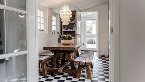 A kitchen with a checkered floor, wooden table, and bench seating. - Family villa behind the Beach. For 3 couples over 30 years old. (Zandvoort)