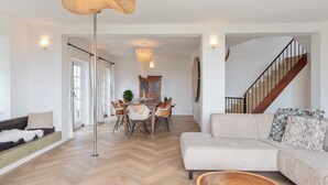A spacious living room with a herringbone floor, a large sofa, a coffee table, and a dining area with a wooden table and chairs. - Family villa behind the Beach. For 3 couples over 30 years old. (Zandvoort)
