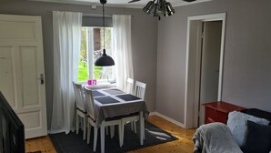 A dining area with a table and chairs, a hanging light fixture, and a view of the outdoors. - Hel Stuga för 4 i Härlig Bymiljö (Dalarnas län)