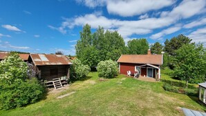A rustic wooden cabin with a red roof, surrounded by lush greenery and trees. - Hel Stuga för 4 i Härlig Bymiljö (Dalarnas län)