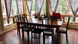 Un comedor con una mesa y sillas de madera, una computadora portátil y un paño rojo.