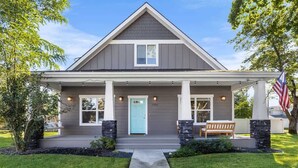 A residential house with a front porch, a blue door, and an American flag. - Family fun home with hot tub, arcade and zipline (Coeur d'Alene)